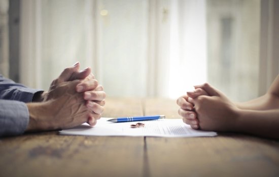 Davis Law Firm Divorce Representation Two people sitting while discussing paperwork. Genevieve Davis is an experienced divorce attorney in Seattle.