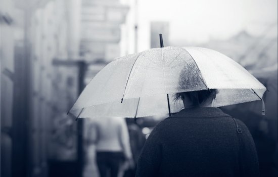 A person walks under a clear umbrella.